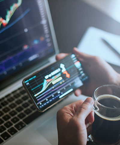 investment stockbroker predicting bitcoin price trend movement using laptop and phone